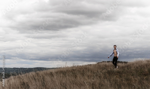 man who feels free in a field on a hill © Yalana