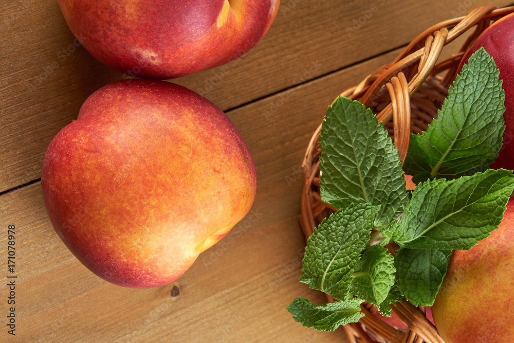 peaches in a wicker basket on wooden table with blurred background peaches in a wicker basket on wooden table with blurred background