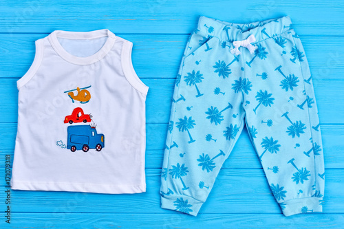 Unisex baby summer outfit. New childs apparel on sale. Children cute summer garment on blue wooden background. © DenisProduction.com