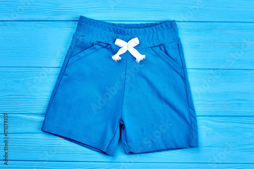 Blue cotton kids shorts. Baby boy casual textile short pants on blue wooden background. Summer apparel for little boys. © DenisProduction.com