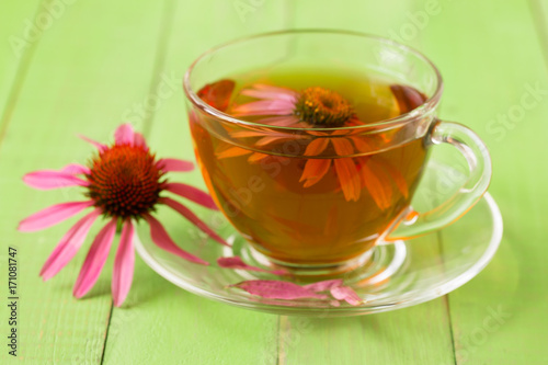 Cup of echinacea tea on green wooden table