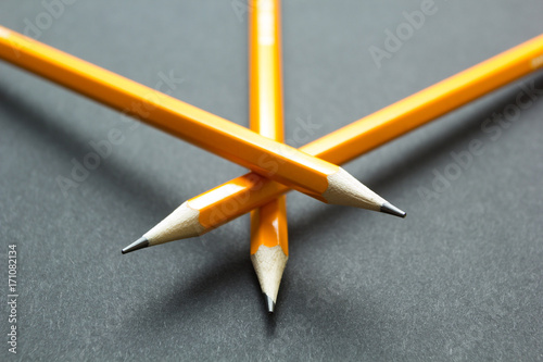 Three yellow pencils on black paper. photo