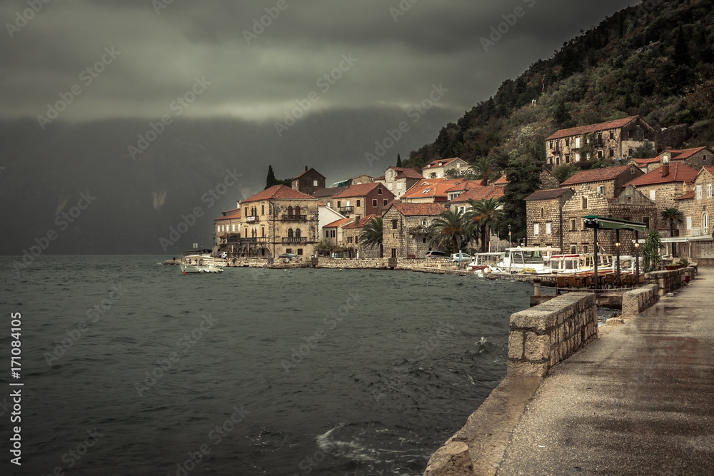 Promenade in old medieval town Perast in rainy overcast day with puddles in Montenegro 