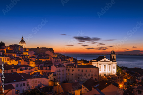 View of the Alfama neighborhood from the Portas do Sol viewpoint at sunrise in Lisbon, Portugal; Concept for travel in Portugal