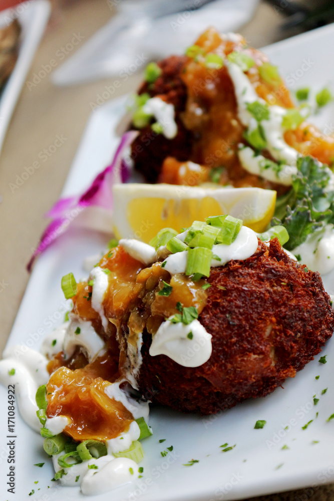 Sour Cream and Chive Topped Crab Cakes with Sliced Lemon and Plated With An Orchid Sour Cream and Chive Topped Crab Cakes with Sliced Lemon and Plated With An Orchid