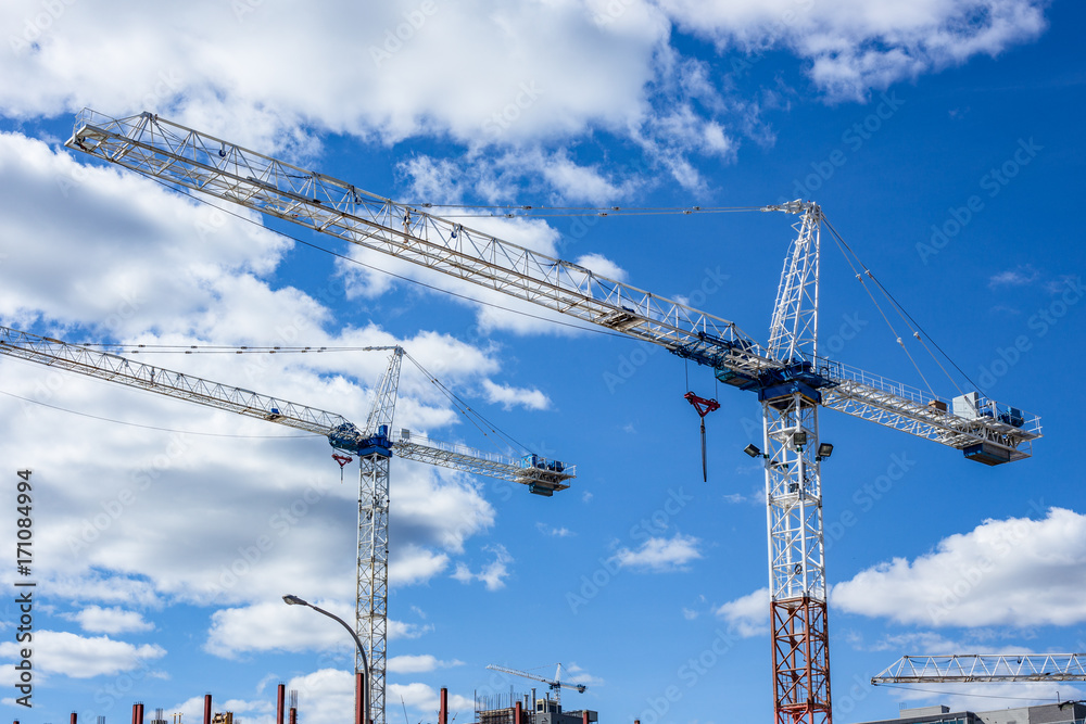 tall cranes on construction site clouds blue sky