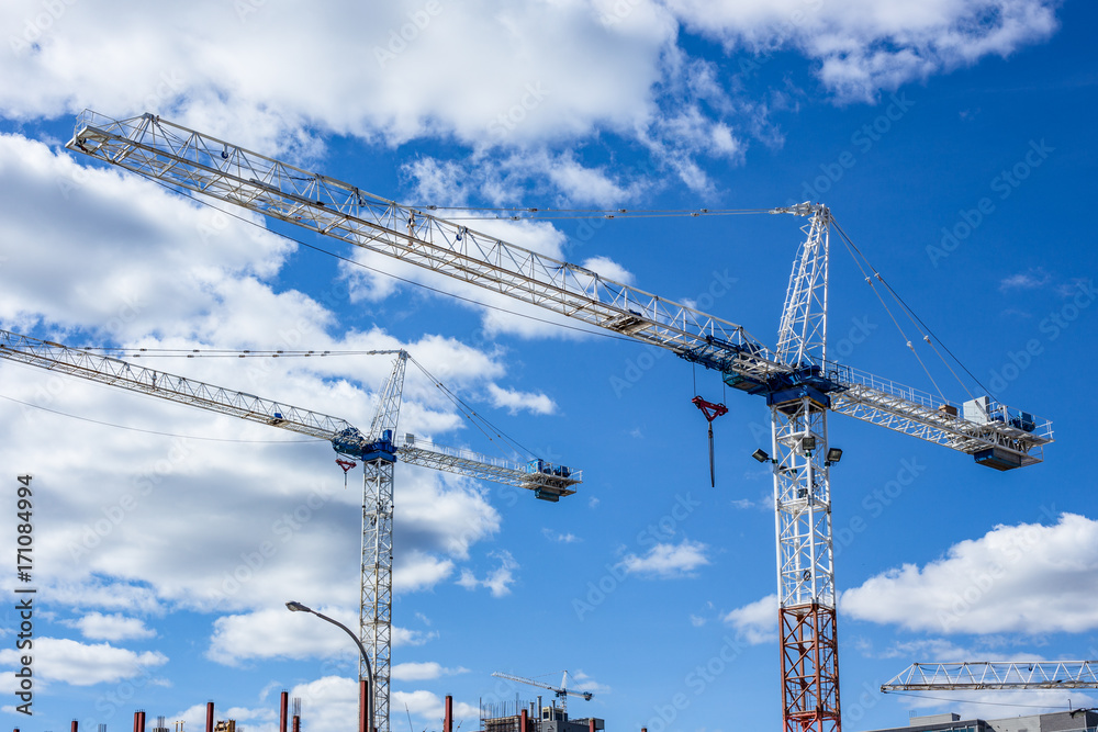 tall cranes on construction site clouds blue sky tall cranes on construction site clouds blue sky