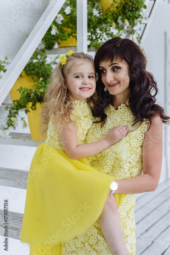 Happy loving family. Mother and her daughter child girl playing and hugging in yellow dresses