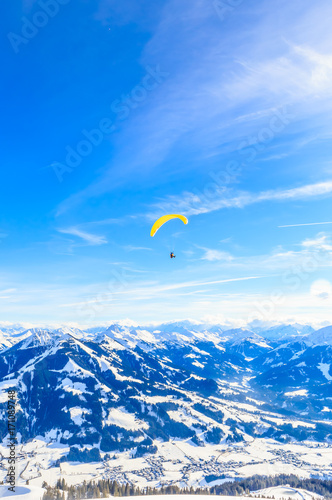 Paragliding over the mountains in winter. Ski resort Hopfgarten, Tyrol, Austria