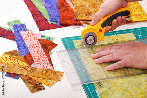 Tablou pe pânză Process cutting fabric pieces by rotary cutter on mat using ruler