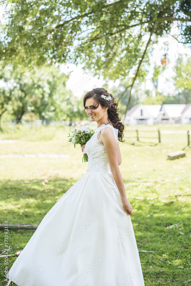 likable and pretty bride in a white wedding dress with a wedding bouquet in his hands on a enjoying romantic moments outside on a summer meadow. wedding day 
