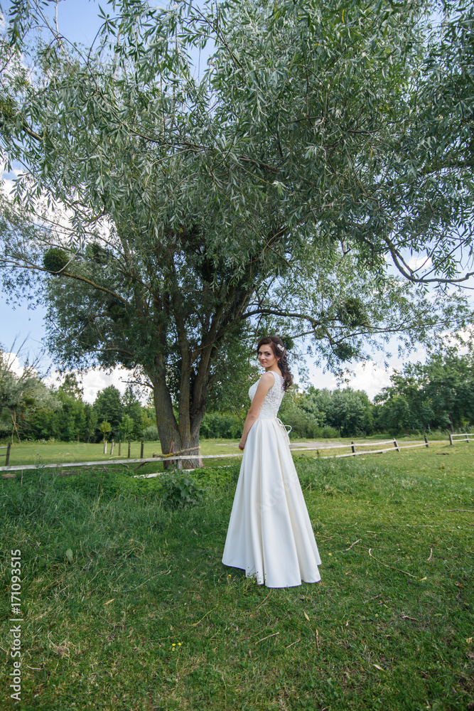 likable and pretty bride in a white wedding dress with a wedding bouquet in his hands on a enjoying romantic moments outside on a summer meadow. wedding day likable and pretty bride in a white wedding dress with a wedding bouquet in his hands on a enjoying romantic moments outside on a summer meadow. wedding day