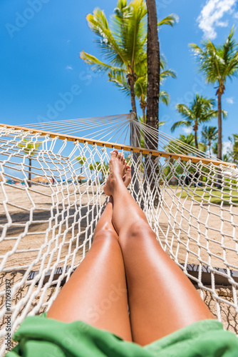 Beach hammock vacation woman feet selfie. Girl relaxing taking pov picture of her legs and feet sun tanning in tropical summer destination. Travel fun getaway.