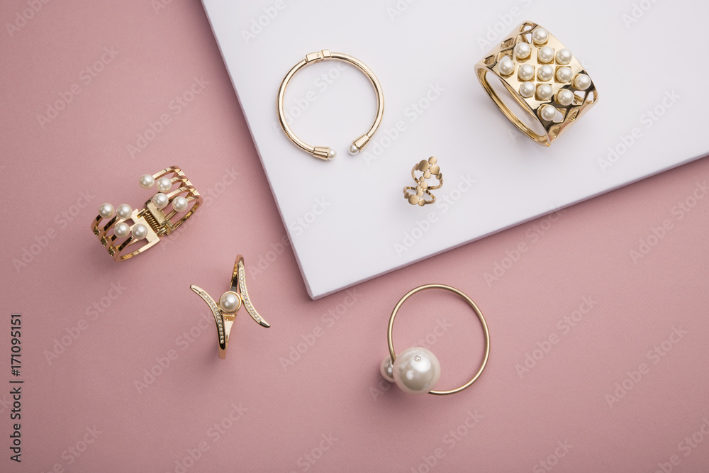 Pearl Golden Bracelets and ring on pink and white background - obrazy, fototapety, plakaty 