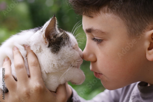 happy boy hold cat smiling close up photo on the summer green garded background photo