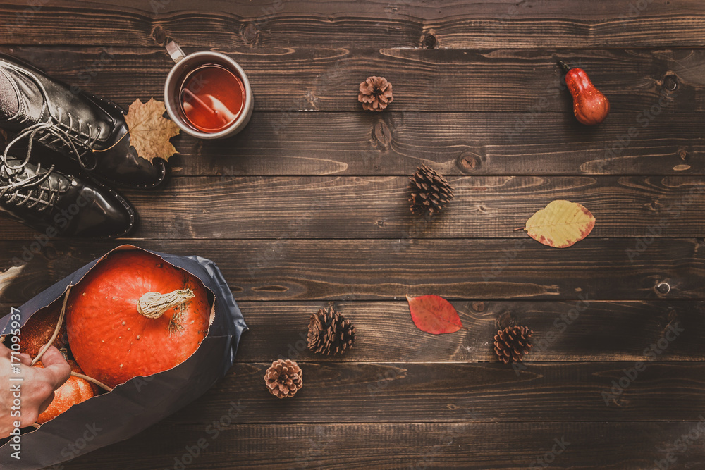 Autumn background with copy space. Female legs, cup of hot tea and pumpkins on the wooden background Autumn background with copy space. Female legs, cup of hot tea and pumpkins on the wooden background