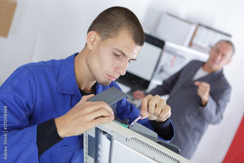 Obraz premium closeup shot young male technician repairing digital photocopier machine