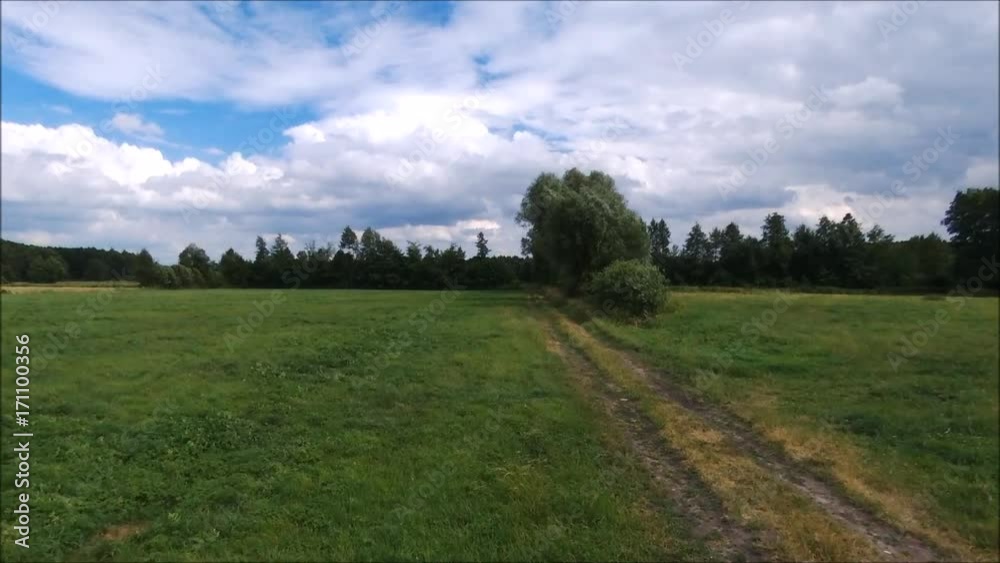 Gravel dirt road through the green meadow. Flight over field at summer day. Poland Gravel dirt road through the green meadow. Flight over field at summer day. Poland