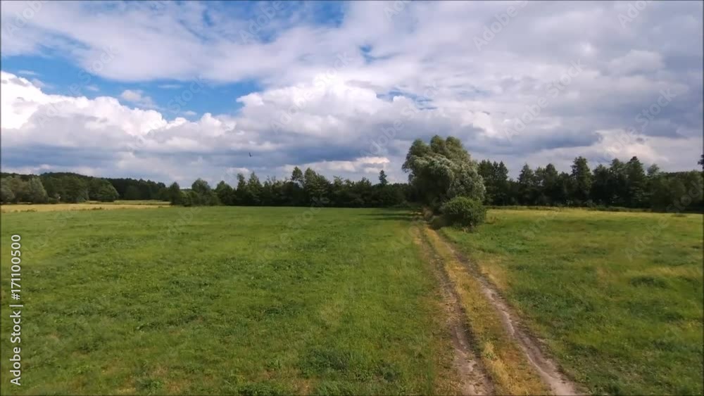 Gravel dirt road through the green meadow. Flight over field at summer day. Poland Gravel dirt road through the green meadow. Flight over field at summer day. Poland