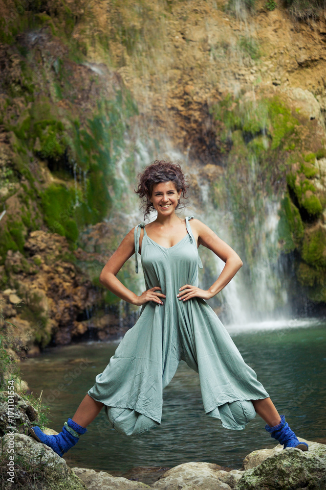 smiling young woman posing  in front of waterfall summer
