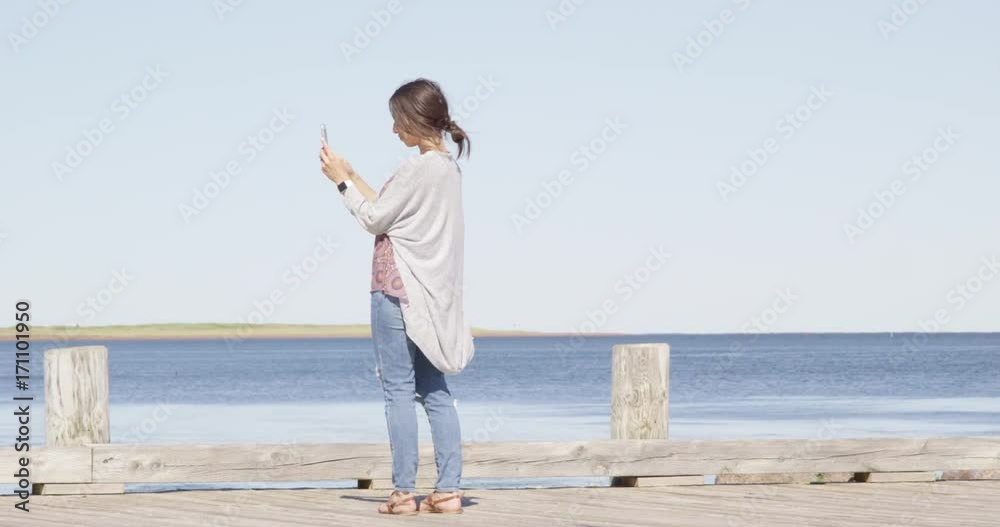 Young woman taking photo of ocean with smart phone - slow motion Young woman taking photo of ocean with smart phone - slow motion