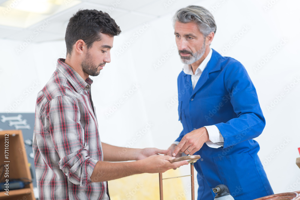 Fototapeta premium factory manager and engineering apprentice discussing component