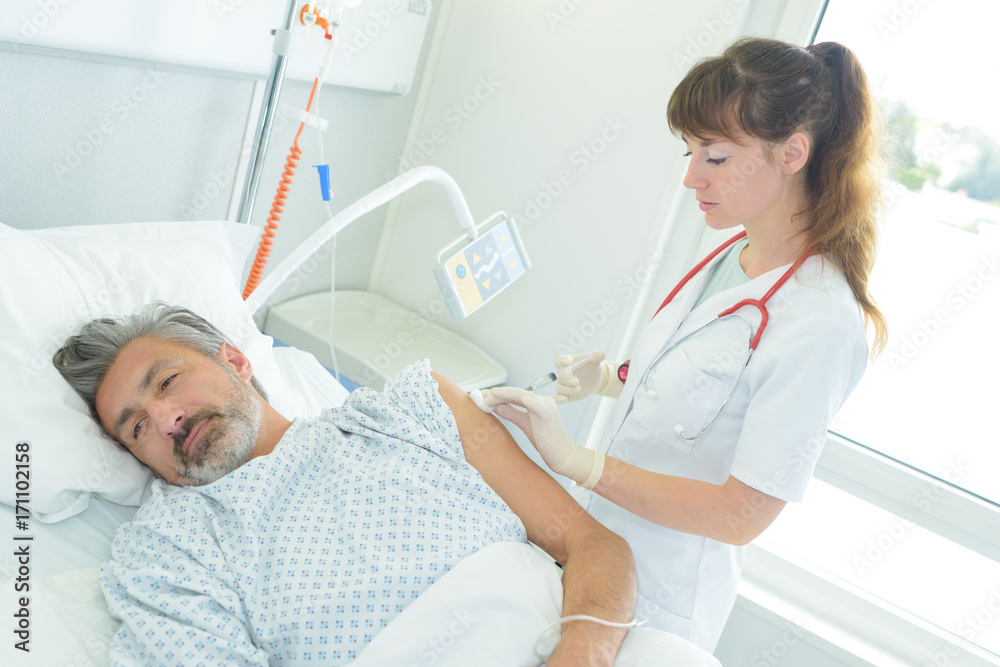 doctor injecting ill man lying in bed doctor injecting ill man lying in bed