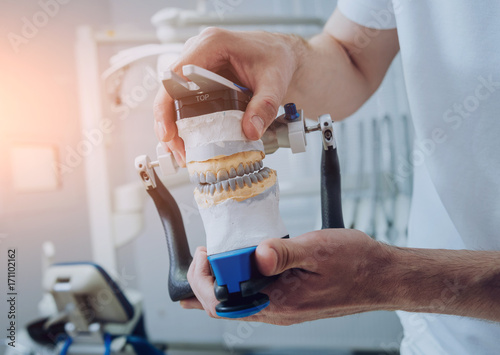 Dental technician working with articulator in dental lab
