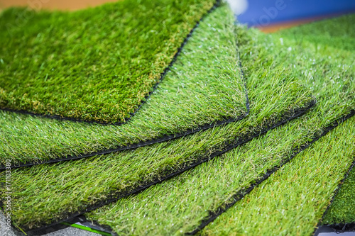 Green artificial turf rolled. Probes examples of artificial turf, floor coverings for playgrounds.
