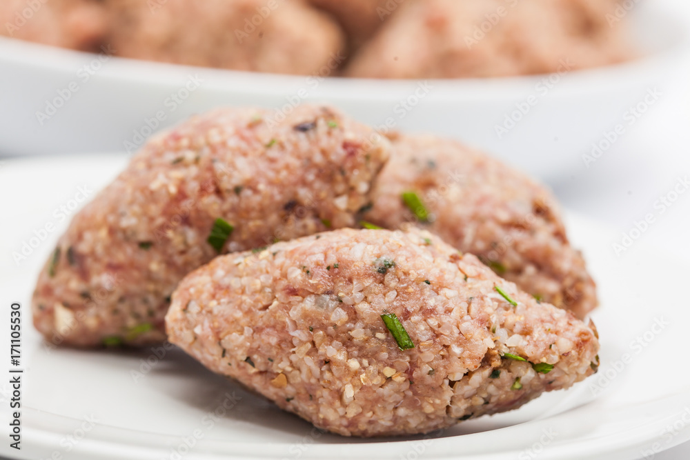 Step by step Levantine cuisine kibbeh preparation : Raw kibbeh balls on white dish Step by step Levantine cuisine kibbeh preparation : Raw kibbeh balls on white dish