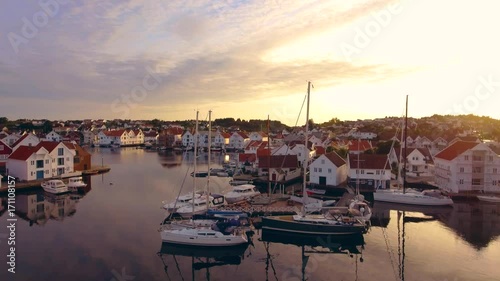 Top view of amazing port city of Skudeneshavn, Norway. Beautiful white yachts and boats stand in the sea harbor. Stunning clear sky and beautiful sunset. Typical European port city, view from above
