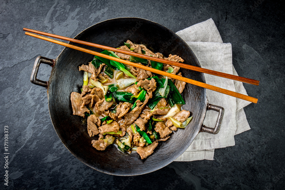 Traditional chinese mongolian beef stir fry in chinese cast iron wok with  cooking chopsticks, stone slate background. Top view, copy space Stock  Photo | Adobe Stock