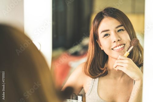 Young Beautiful Asian Woman making make-up near mirror
