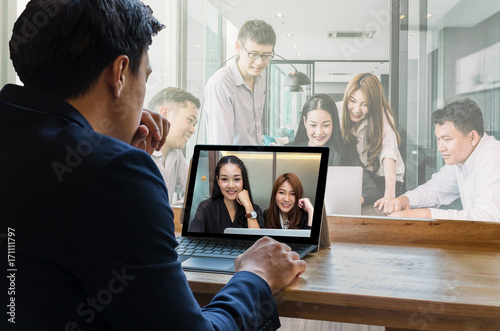 Businessman sitting and using computer laptop showing Group of asian Business team having video conference via monitor display in the modern conference room, Business people meeting concept