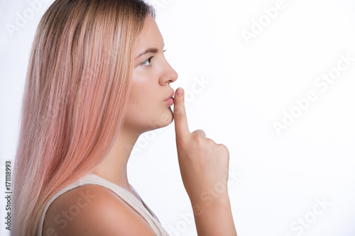 Young beautiful woman has put forefinger to lips as sign of silence. Shhh concept