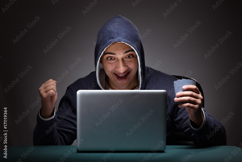 Young man wearing a hoodie sitting in front of a laptop computer Young man wearing a hoodie sitting in front of a laptop computer