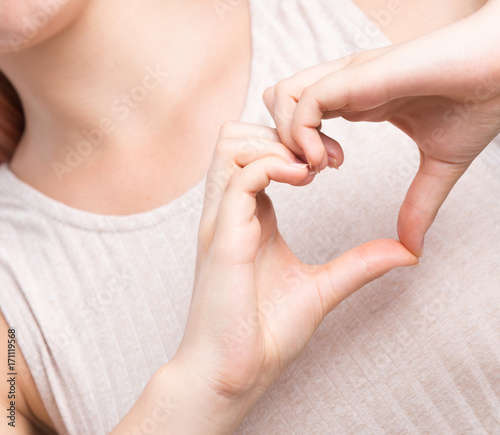 Closeup of girl make a heart with her hands over white background