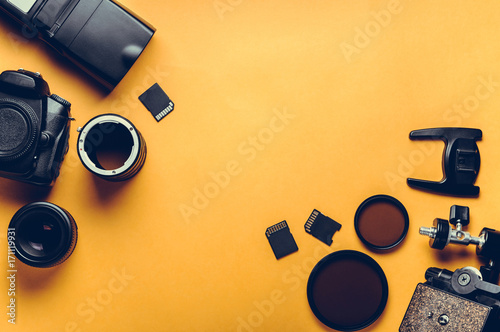 Digital camera, lenses and equipment of the photographer on a yellow background