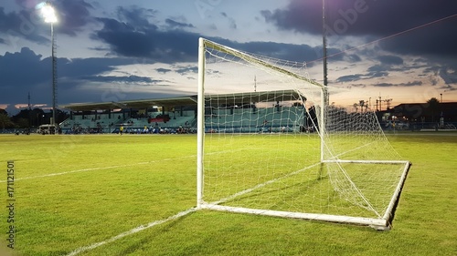 Football goal with the white mesh on a green lawn in the evening