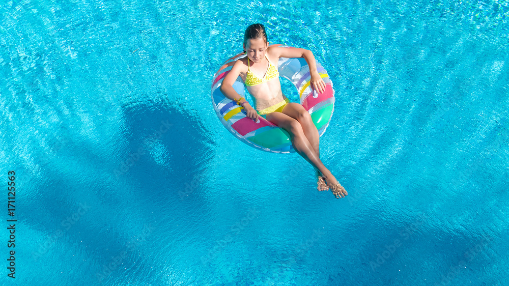 © Iuliia Sokolovska - Aerial view of girl in swimming pool from above, kid swim on inflatable ring donut and has fun in water on family vacation