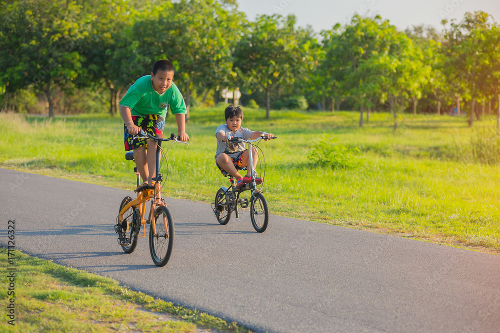 Two boys are riding their bicycles on holiday with fun in the park.
