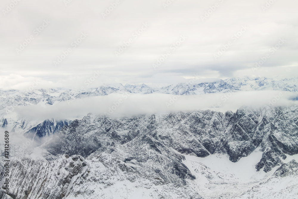 View of a mountain range with snow and clouds