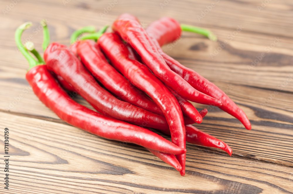 Heap of wholes red fresh ripe chili pepper on old brown wooden rustic planks Heap of wholes red fresh ripe chili pepper on old brown wooden rustic planks