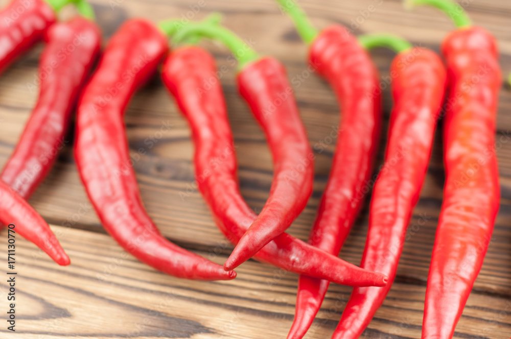 Row of wholes red fresh ripe chili pepper on old brown wooden rustic planks Row of wholes red fresh ripe chili pepper on old brown wooden rustic planks