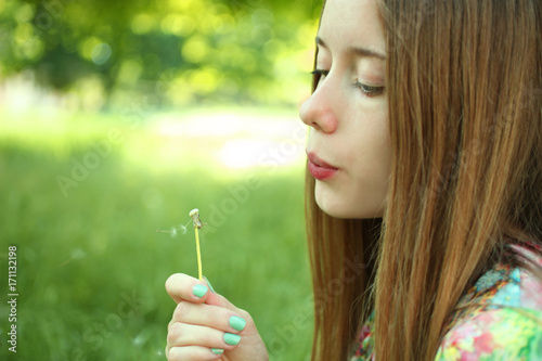 Girl blowing on a dandelion.