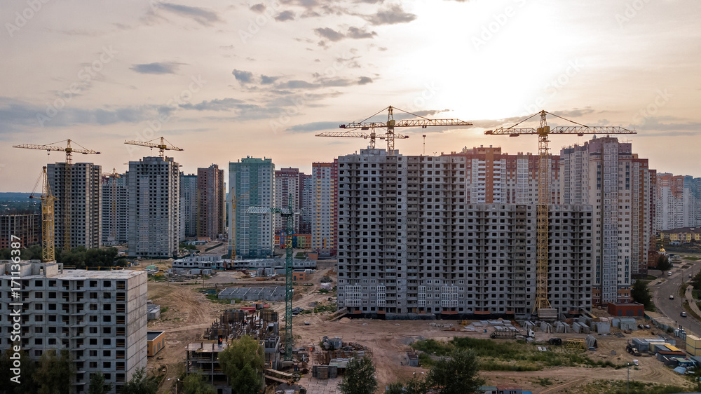 Aerial view of construction site of residential area buildings with cranes at sunset from above, urban skyline of Kyiv city, Ukraine
