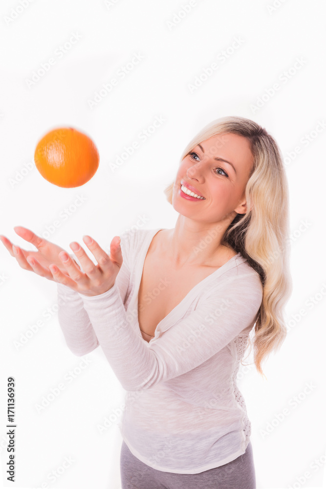 Portrait of young divine blonde woman who tossing an orange against the white background Portrait of young divine blonde woman who tossing an orange against the white background