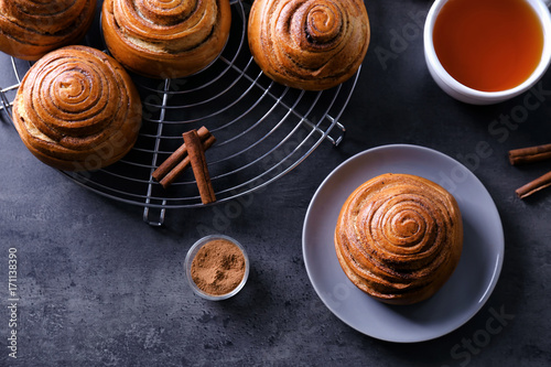 Beautiful composition with sweet cinnamon rolls and cup of tea on table
