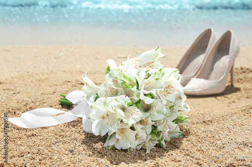Fototapeta Naklejka Na Ścianę i Meble -  Beautiful bouquet and high heel shoes on sand. Beach wedding concept