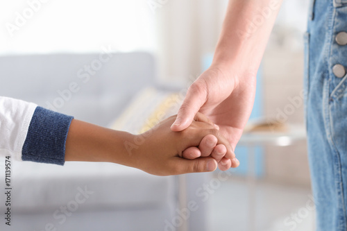 Woman holding hand of small African-American child. Adoption concept © Africa Studio